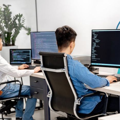 Developers working at desks with large monitors